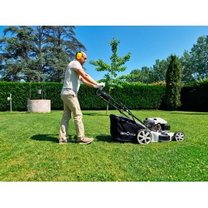 Uomo utilizza tosaerba a scoppio in giardino.