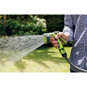 Pistola a spruzzo verde t.b.t. in azione mentre annaffia un giardino.