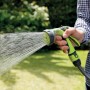 Pistola a spruzzo verde t.b.t. in azione mentre annaffia un giardino.
