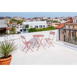 Set di mobili da giardino rosa con tavolo e due sedie su una terrazza panoramica.