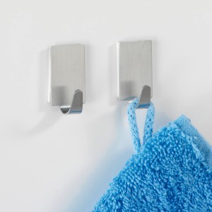 Set di 4 ganci rettangolari Wenko in acciaio inox opaco, uno con asciugamano blu.