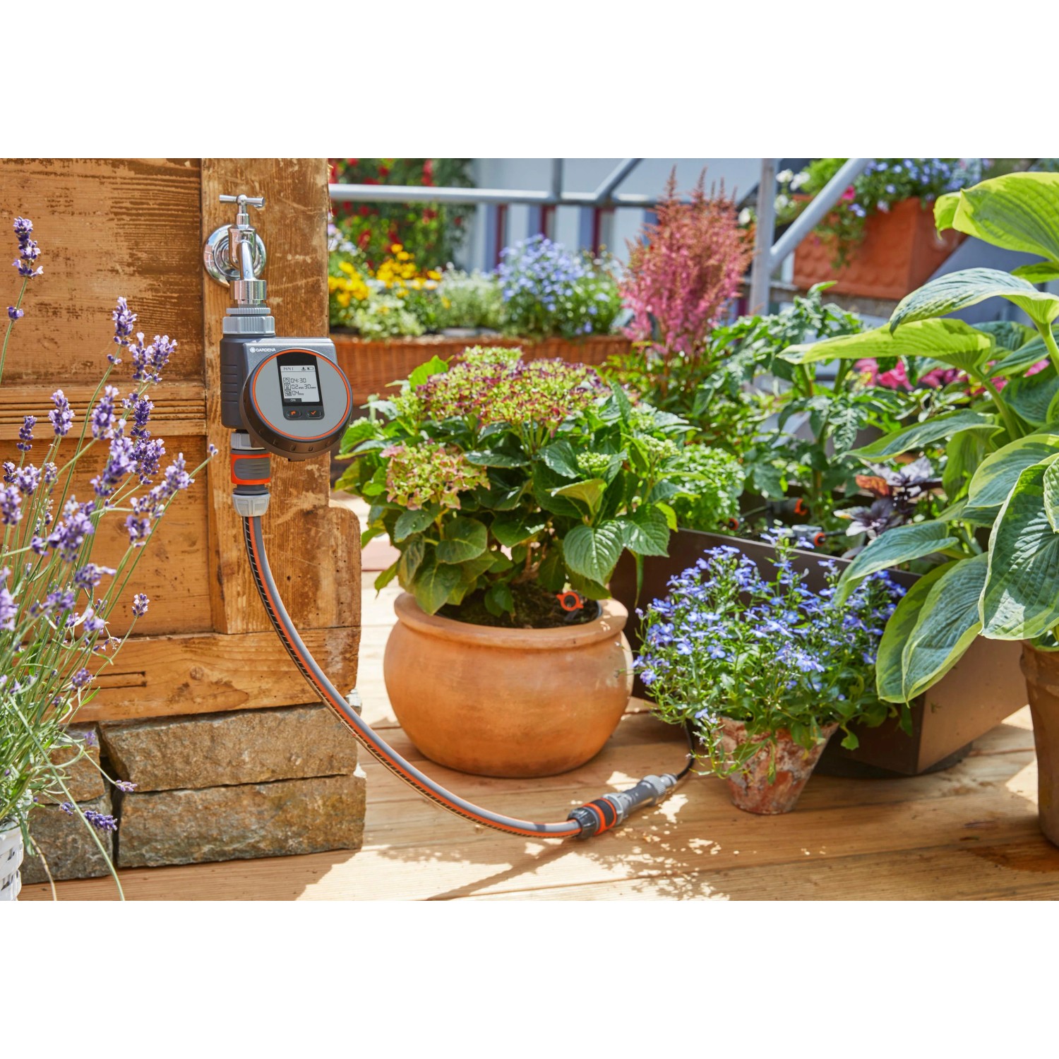 Computer per irrigazione Gardena Flex su rubinetto con piante sullo sfondo.