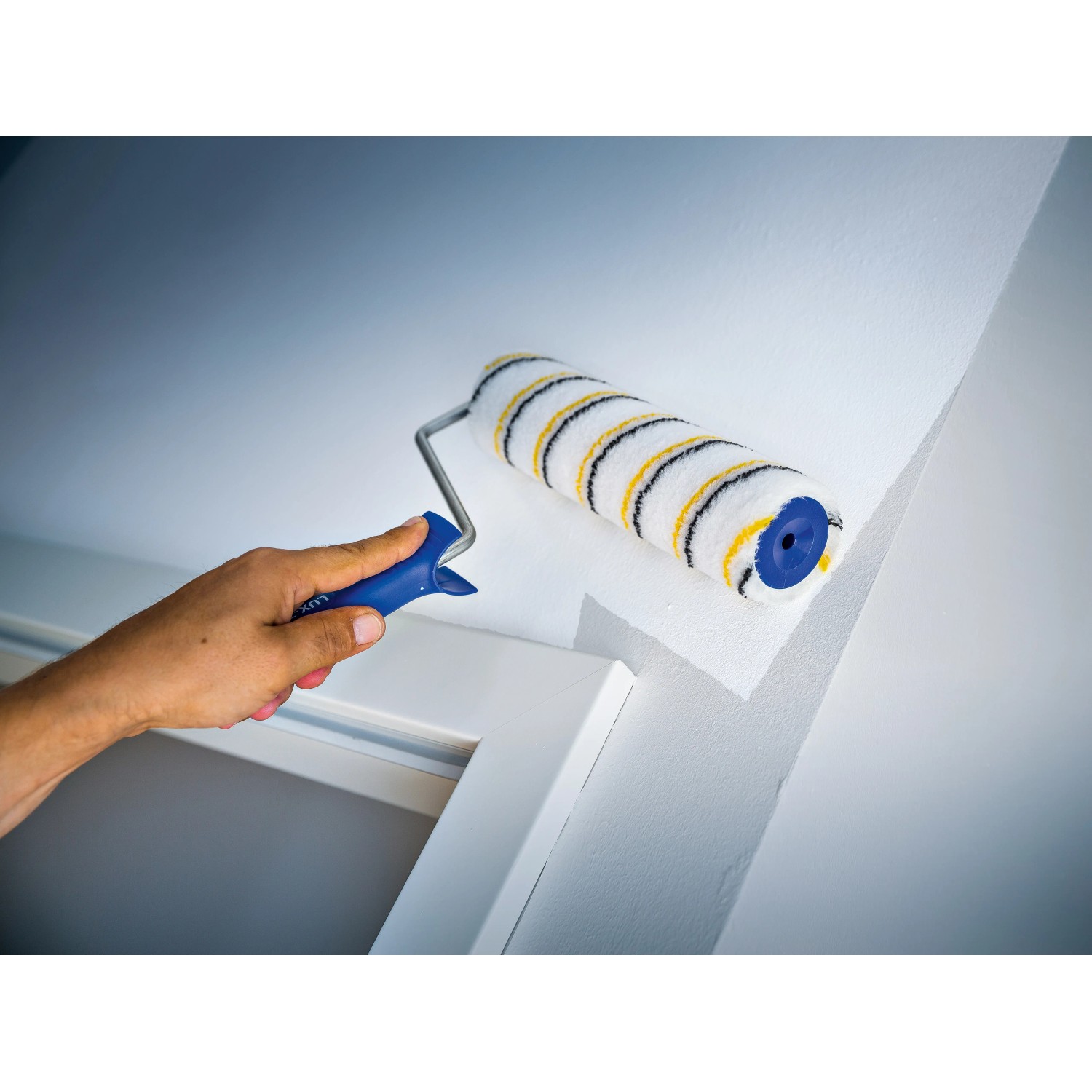 Rullo per pittura LUX 25cm mentre dipinge una parete, Polymix, oro-grigio a righe.