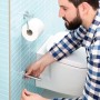 Uomo che installa il porta rotolo di ricambio Tesa Smooz cromato in bagno.