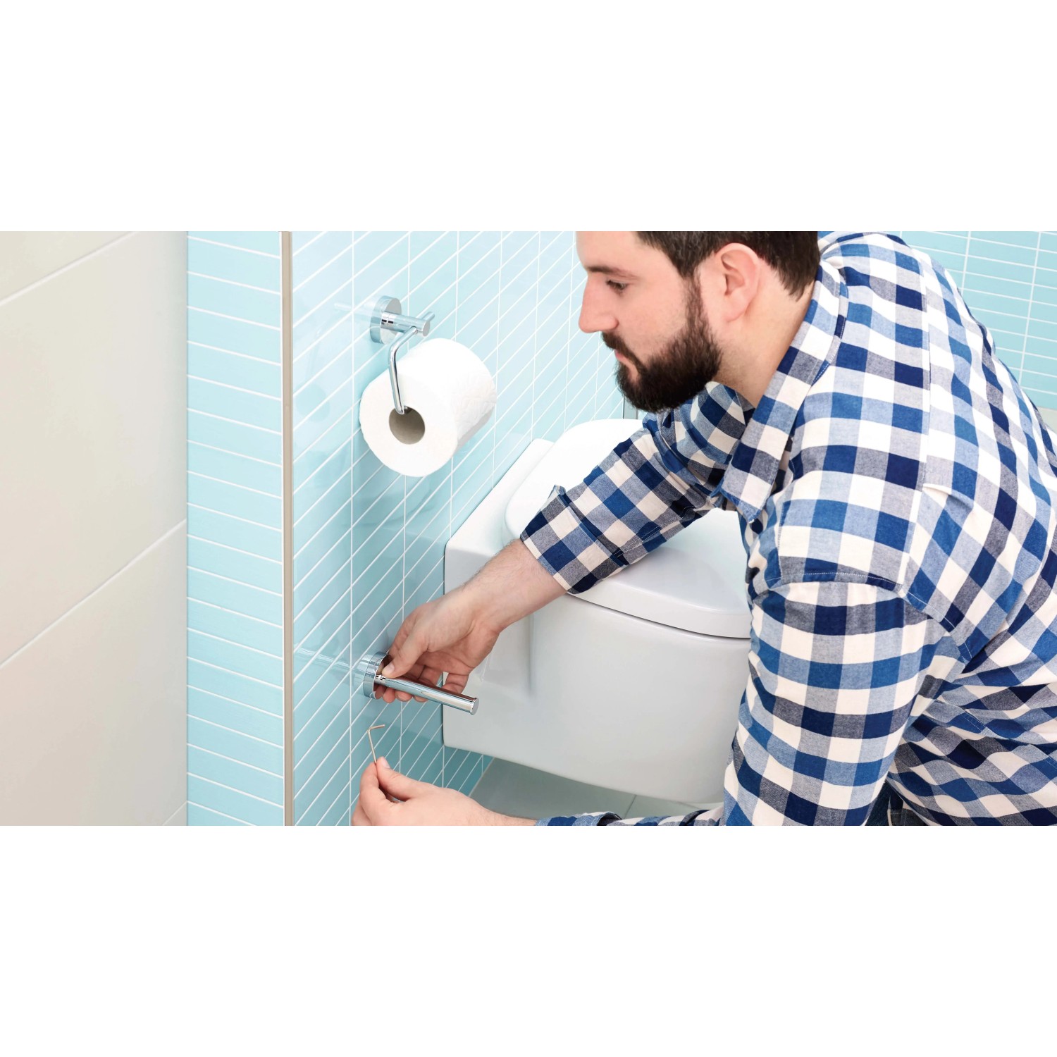 Uomo che installa il porta rotolo di ricambio Tesa Smooz cromato in bagno.
