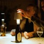 Scena da tavolo con luce da esterno t.b.t. a forma di bottiglia, che illumina un gruppo di persone che giocano a carte.
