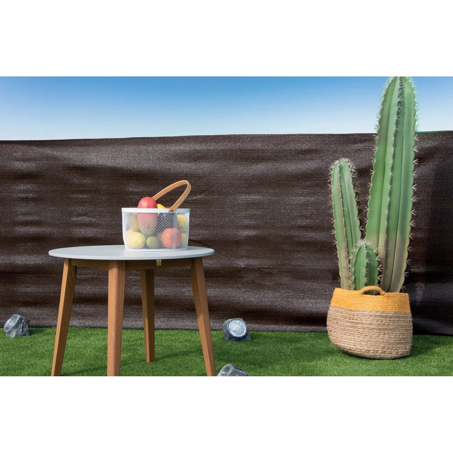 Paravista t.b.t. marrone scuro in giardino con tavolo, cactus e cesto di frutta.