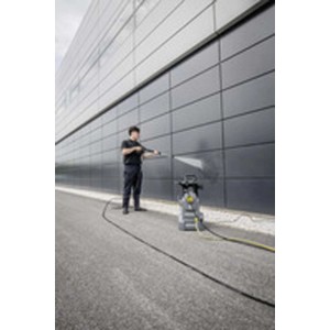 Uomo pulisce facciata con idropulitrice. Il dispositivo è grigio e giallo.