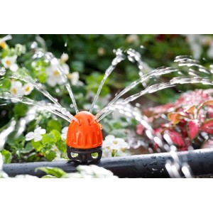 Irrigatore a microirrigazione arancione in uso, annaffia le piante.