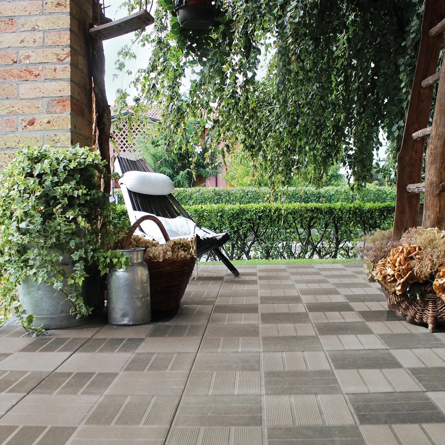 Pavimenti autobloccanti t.b.t. posati su una terrazza con mobili da giardino sullo sfondo.