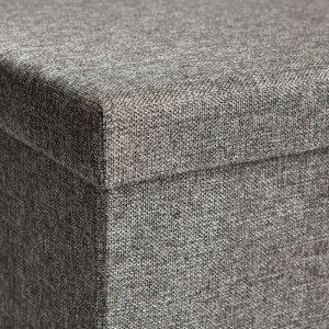 Dettaglio di un pouf grigio con rivestimento in tessuto.