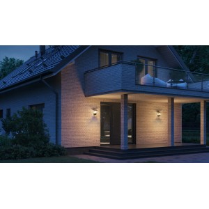 Lampada da esterno nera Steinel L 10 S su una parete di casa con la luce accesa.