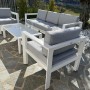 Set di mobili da giardino bianchi con divano, poltrone e tavolo per esterni.
