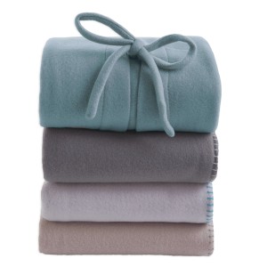 Coperte/plaid t.b.t. impilate in blu, grigio, bianco e beige con fiocco.