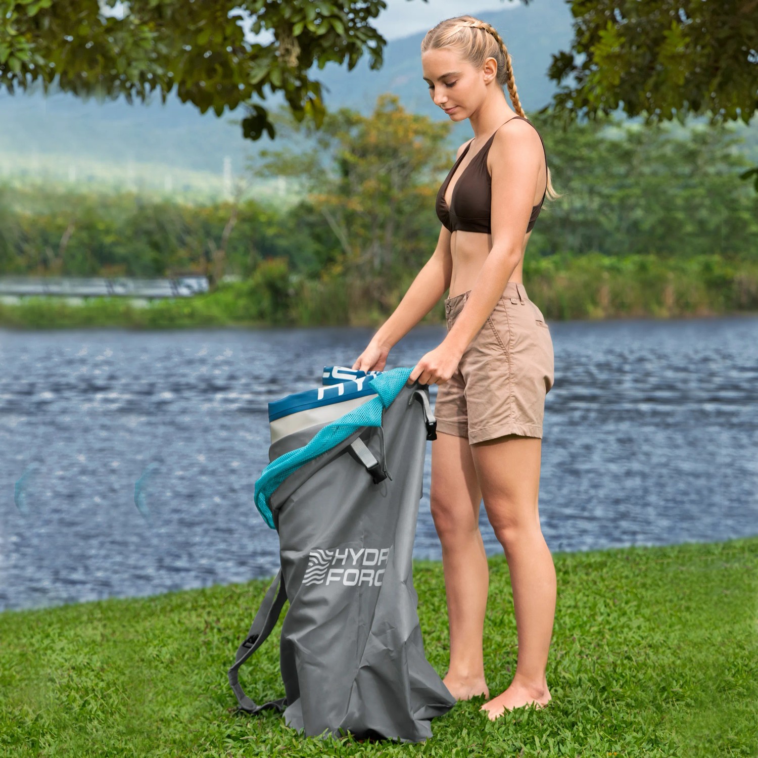 Donna che ripone il set Bestway SUP Aqua Drifter nello zaino in riva al lago.