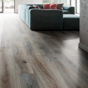 Piastrelle per pavimenti chiare effetto legno posate in un soggiorno con divano.