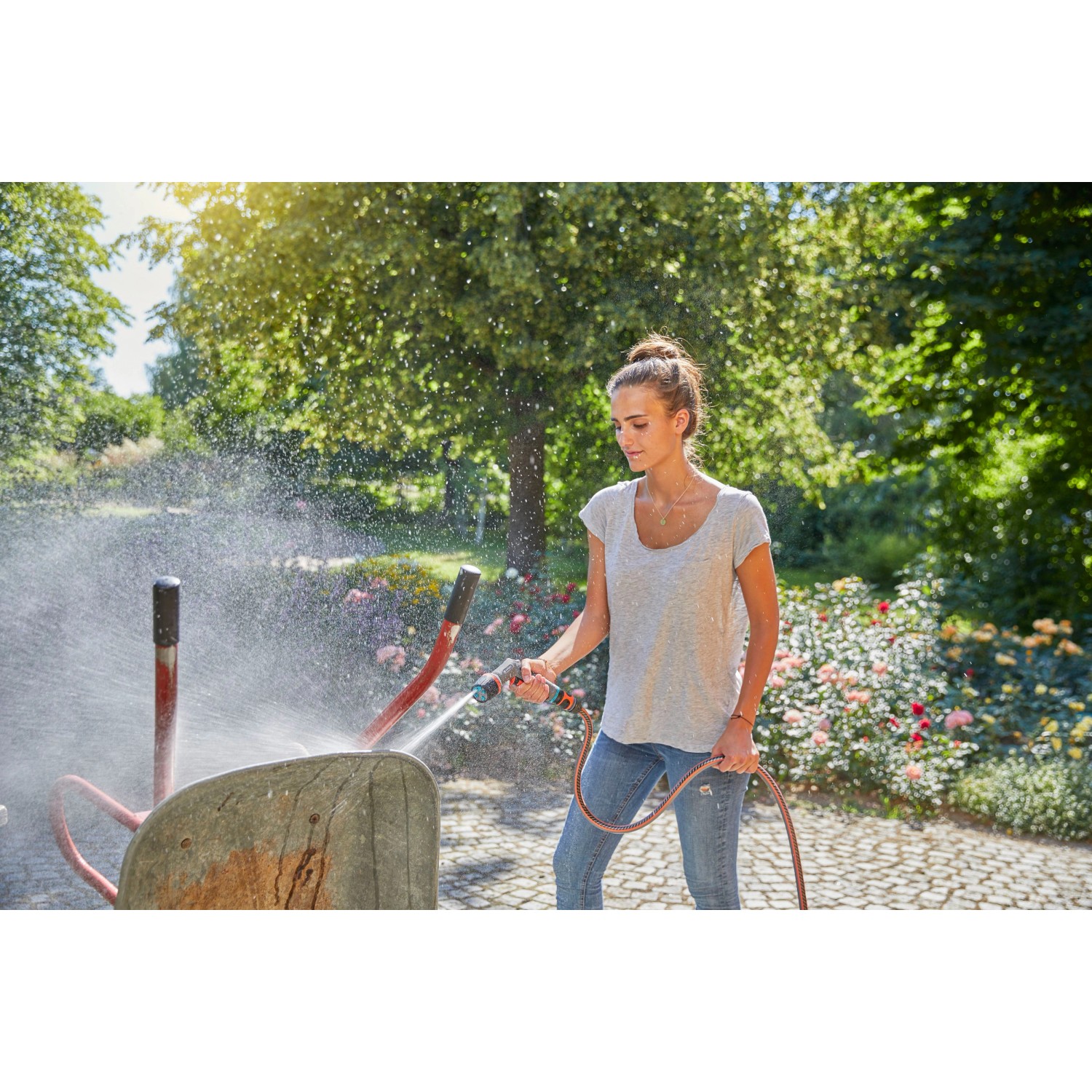 Donna pulisce carriola con Gardena Comfort Cleaning Sprayer ecoPulse™ in giardino.