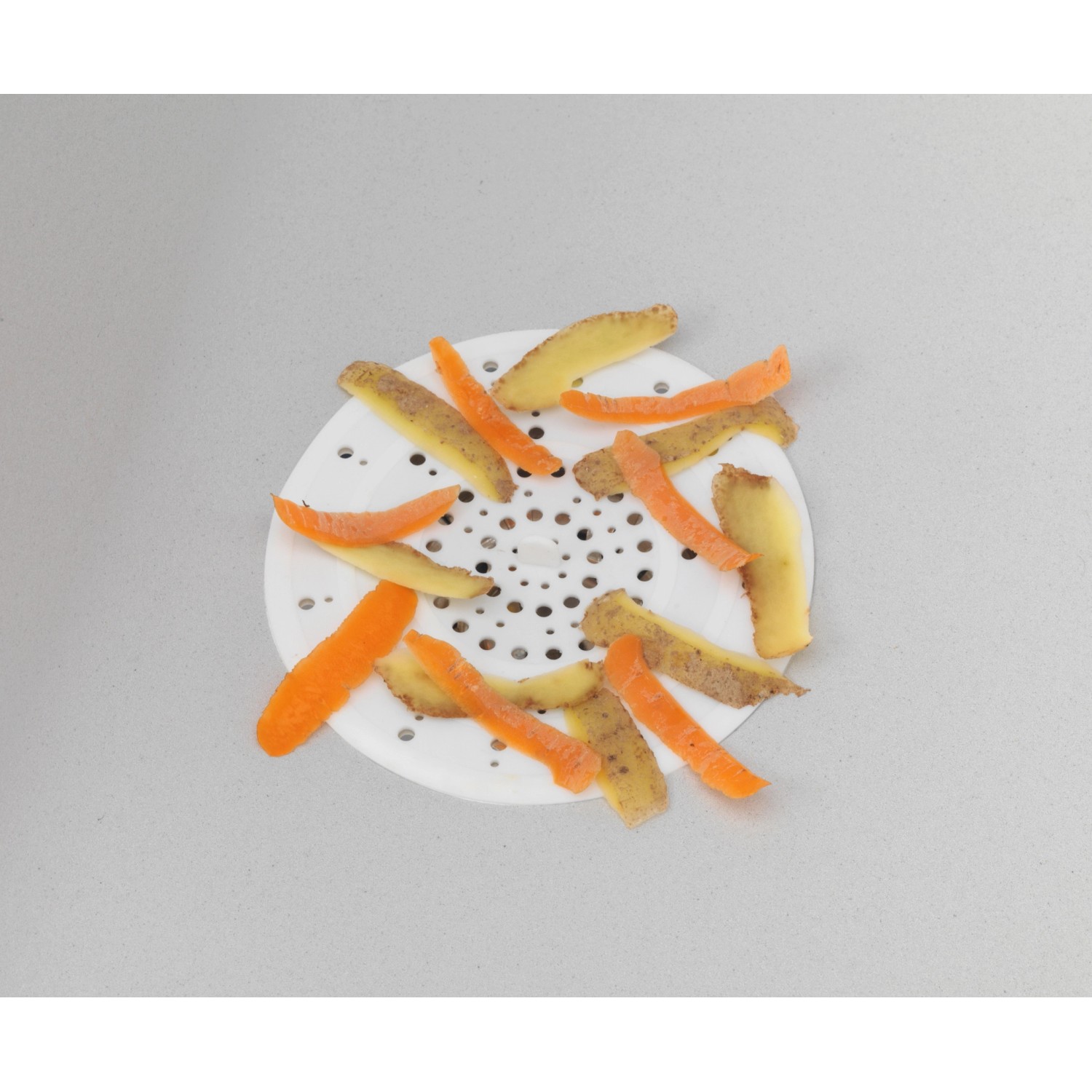 Filtro di scarico bianco Wenko in silicone con bucce di verdure e patate nel lavandino.
