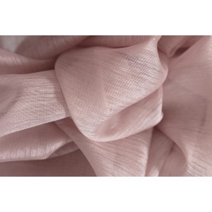 Dettaglio di una tenda in tessuto leggero e semitrasparente color rosa tenue.