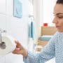 Donna che prende carta igienica da un porta carta igienica t.b.t. in bagno.