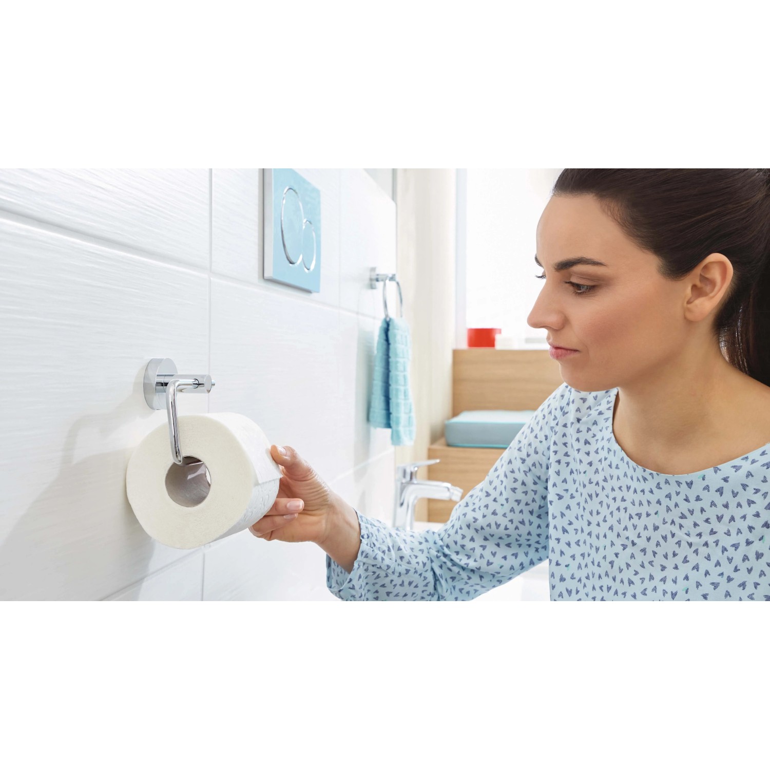 Donna che prende carta igienica da un porta carta igienica t.b.t. in bagno.