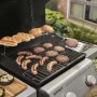 Barbecue a gas con salsicce, hamburger e panini sulla griglia.