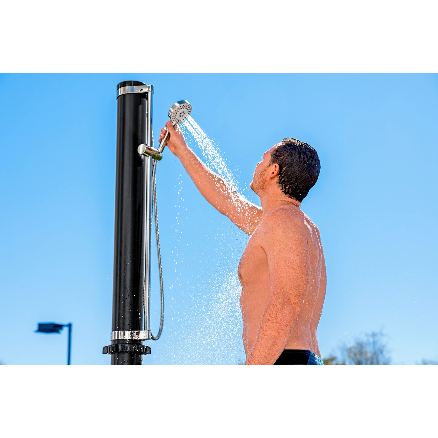 Doccia da giardino Bestway Solarflow con serbatoio da 20 l in uso: uomo che fa la doccia sotto il cielo blu.
