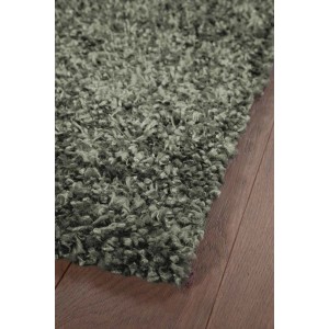 Dettaglio di un tappeto a pelo lungo grigio t.b.t. su pavimento in legno.