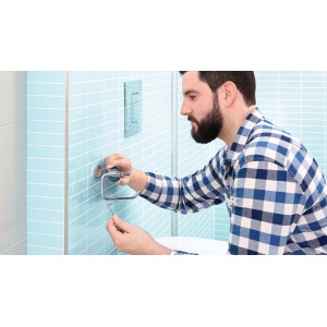 Uomo che installa un porta carta igienica t.b.t. in bagno.