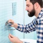 Uomo che installa un porta carta igienica t.b.t. in bagno.