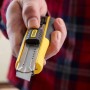 Cutter Stanley FatMax 18 mm, nero-giallo, con lama in mano.