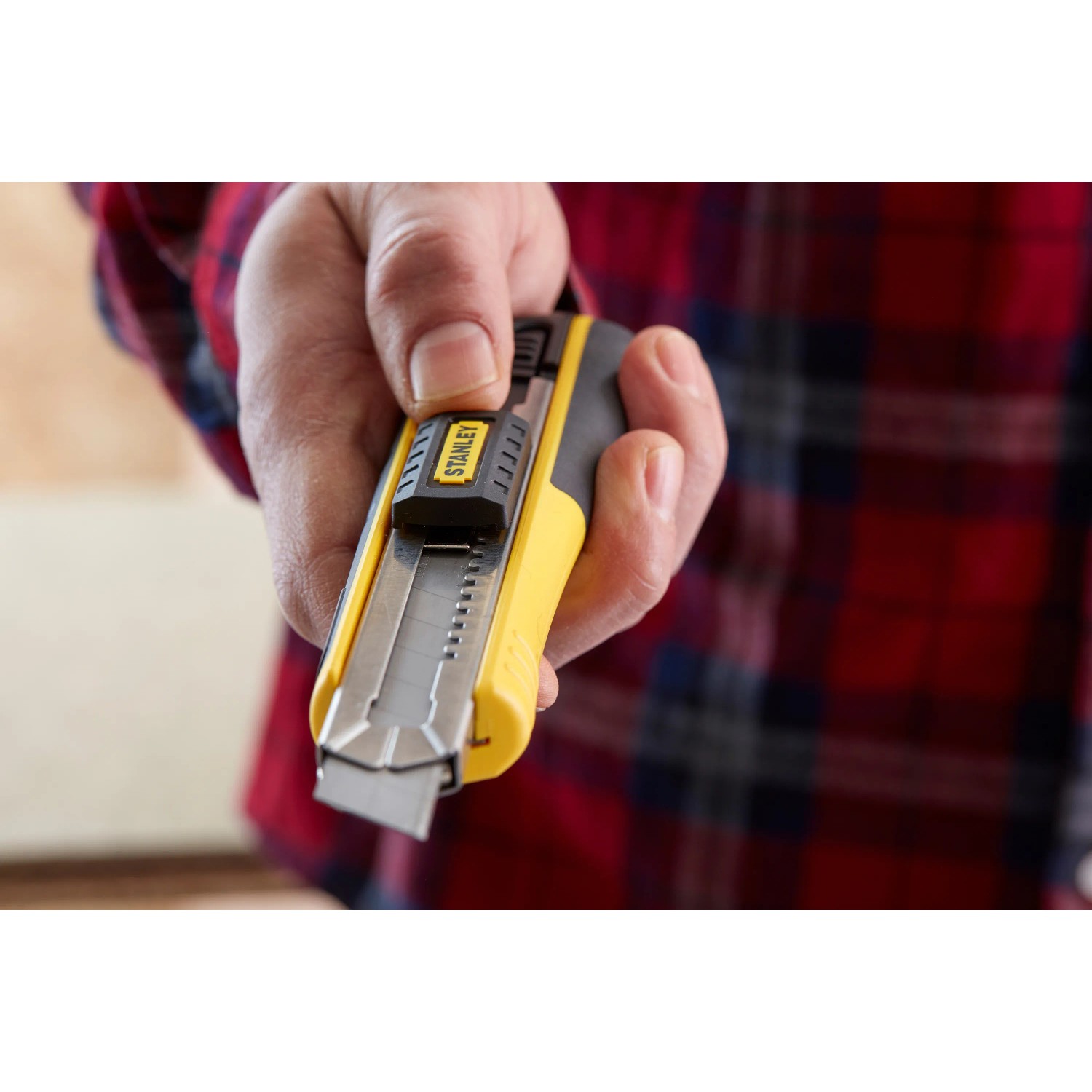 Cutter Stanley FatMax 18 mm, nero-giallo, con lama in mano.