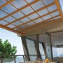 Copertura per patio con pannelli in plastica trasparente e telaio in legno.