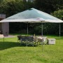 Tenda da campeggio Coleman FastPitch OnePush Shelter L verde e bianca con tavolo e sedie in giardino.