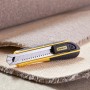 Cutter Stanley FatMax 18mm, nero-giallo, con lame a segmenti su tappeto.