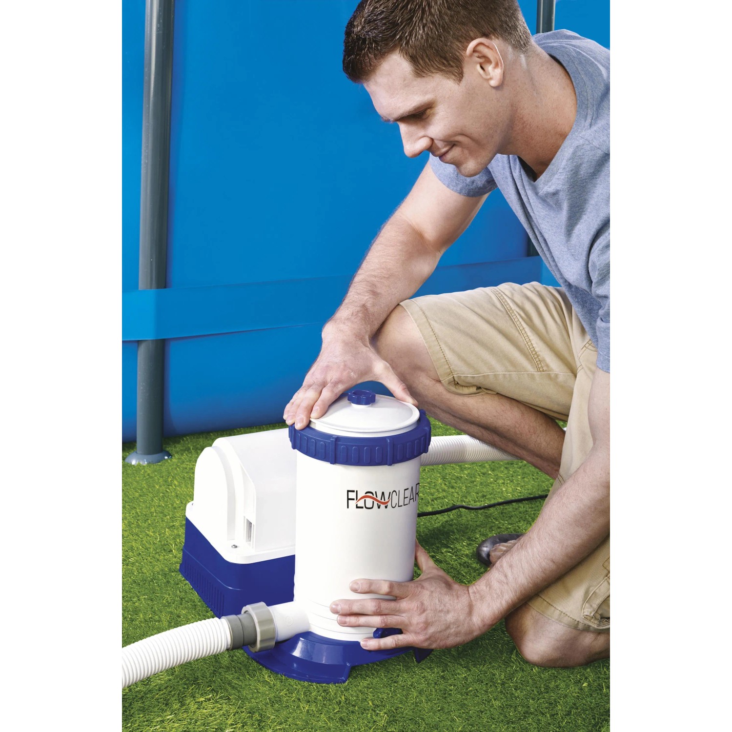 Uomo installa filtro a cartuccia Flowclear sulla piscina. Sistema di filtraggio bianco e blu.