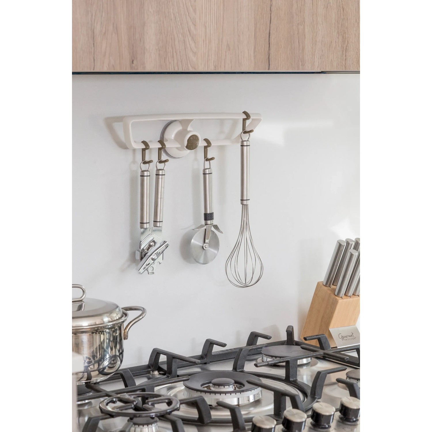 Set di utensili da cucina su barra: rotella tagliapasta, pelapatate, frusta. Sistemazione cucina.