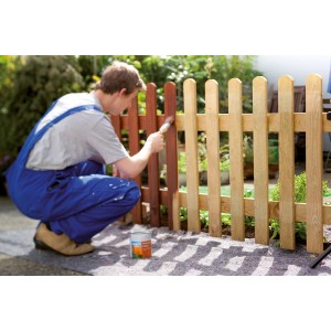 Uomo che dipinge la recinzione su LUX Abdeckvlies. Il vello protettivo 1 m x 25 m protegge dagli schizzi di vernice.