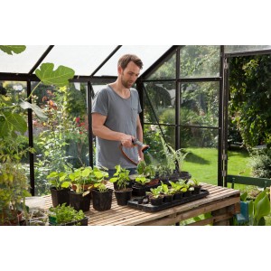 Uomo che annaffia piante con Gardena Comfort in serra.