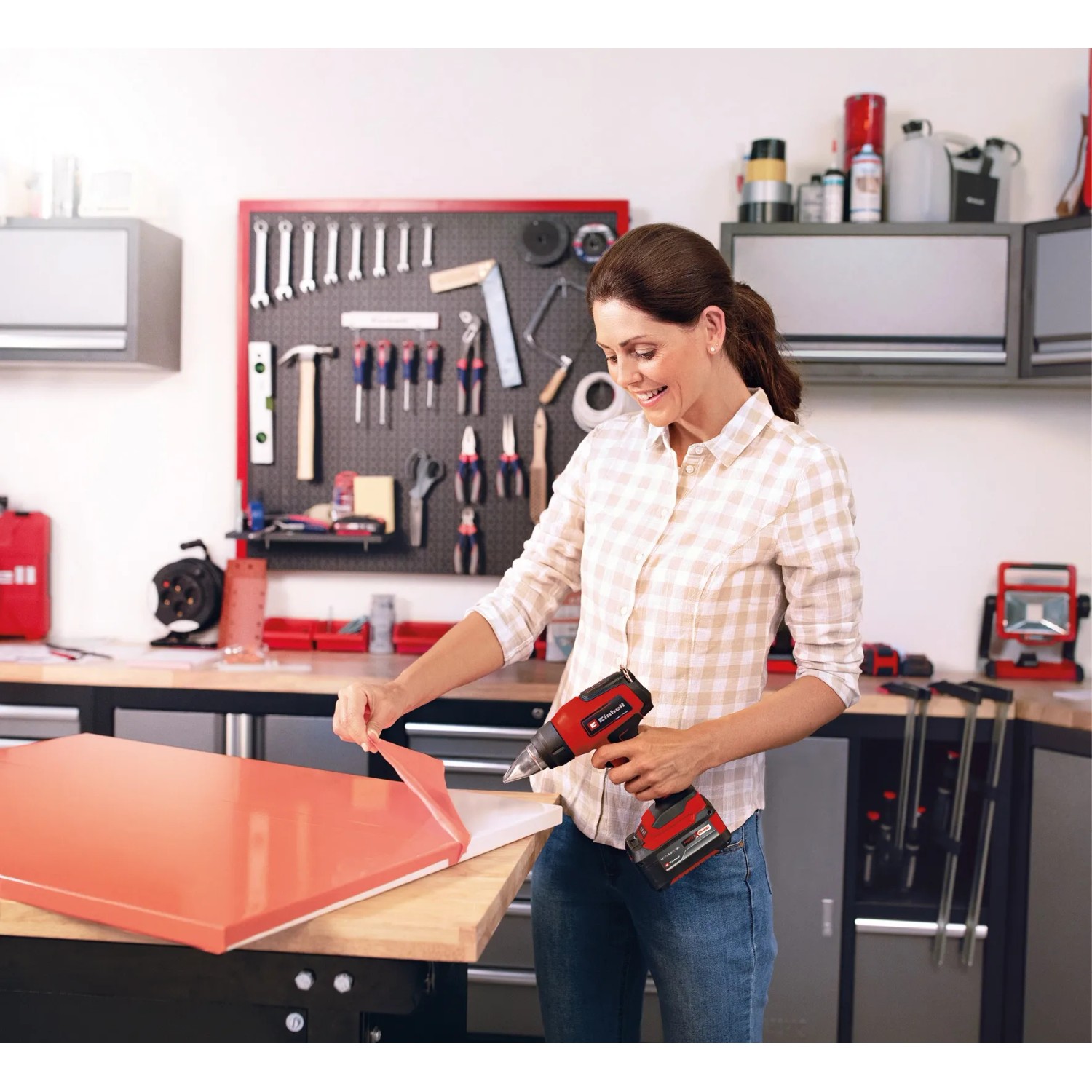 Donna rimuove pellicola con pistola ad aria calda a batteria Einhell TE-HA 18 Li Solo in officina.