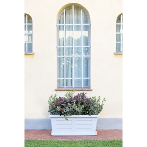 Fioriera da esterno t.b.t. bianca con piante davanti a un muro.