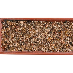 Ciottoli e granulati: Piccoli ciottoli decorativi misti in un vassoio marrone.