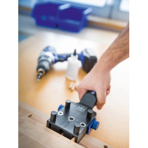 Dima per tasselli LUX Classic in plastica applicata su legno, trapano sullo sfondo.