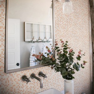 Bagno con piastrelle a mosaico beige e specchio.