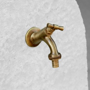 Dettaglio di un rubinetto in ottone su una fontana da giardino.