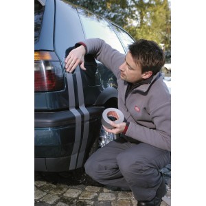 Uomo applica nastro telato universale Tesa Extra Power argento su un'auto. Nastro versatile.