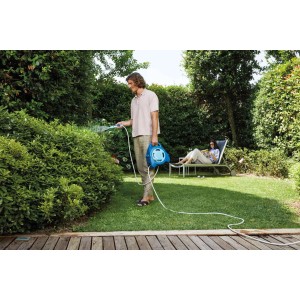 Uomo che innaffia il giardino con avvolgitubo blu. Relax in giardino.