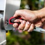 Forbici da carne Char-Broil in azione: mano che apre la griglia. Utensile da barbecue versatile con manico rosso.