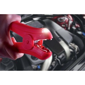 Pinza per batteria rossa con luce LED davanti al vano motore di un'auto. Parte dell'impianto elettrico auto.