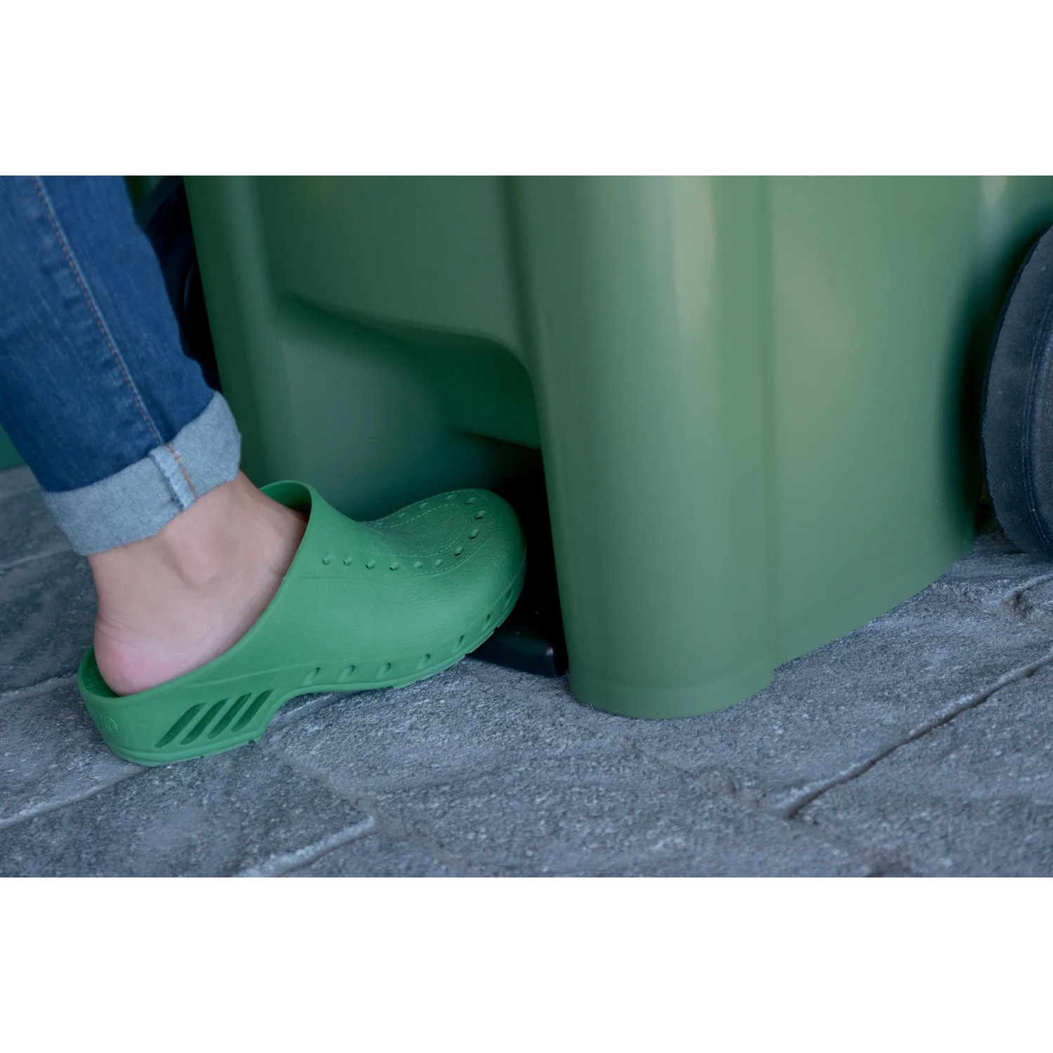 Piede che aziona il pedale di un bidone verde. Pattumiere con pedale.